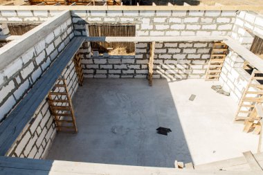 İnşaat halindeki bir evin inşaatı. Beyaz havalandırmalı beton bloklardan yapılmamış ev duvarları. Yönetim kurulları ve Avrupa paletlerinden toplanmış işçiler için yapı iskelesi. en üstteki görünüm.