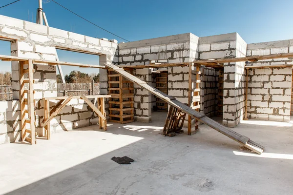 İnşaat halindeki bir evin inşaatı. Beyaz havalandırmalı beton bloklardan yapılmamış ev duvarları. Yönetim kurulları ve Avrupa paletlerinden toplanan işçilerin yapı iskelesi