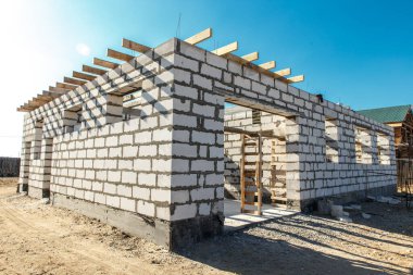 İnşaat halindeki bir evin inşaatı. Köşedeki bitmemiş ev duvarları beyaz havalandırmalı beton bloklardan yapılmış..