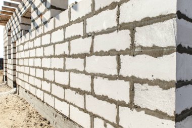 İnşaat halindeki bir evin inşaatı. Köşedeki bitmemiş ev duvarları beyaz havalandırmalı beton bloklardan yapılmış.