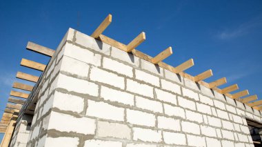 İnşaat halindeki bir evin inşaatı. Köşedeki bitmemiş ev duvarları beyaz havalandırmalı beton bloklardan yapılmış..