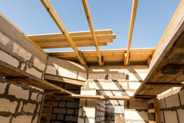 İnşaat halindeki bir evin inşaatı. Beyaz havalandırmalı beton bloklardan yapılmamış ev duvarları. Yönetim kurulları ve Avrupa paletlerinden toplanan işçilerin yapı iskelesi