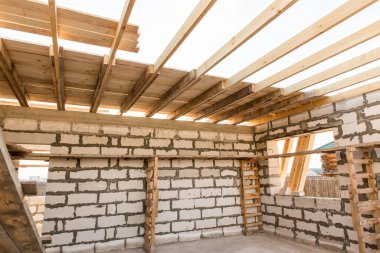 İnşaat halindeki bir evin inşaatı. Beyaz havalandırmalı beton bloklardan yapılmamış ev duvarları. Yönetim kurulları ve Avrupa paletlerinden toplanan işçilerin yapı iskelesi