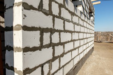 İnşaat halindeki bir evin inşaatı. Köşedeki bitmemiş ev duvarları beyaz havalandırmalı beton bloklardan yapılmış..