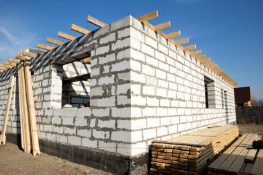 İnşaat halindeki bir evin inşaatı. Köşedeki bitmemiş ev duvarları beyaz havalandırmalı beton bloklardan yapılmış.