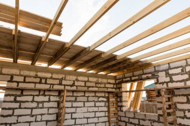 İnşaat halindeki bir evin inşaatı. Beyaz havalandırmalı beton bloklardan yapılmamış ev duvarları. Yönetim kurulları ve Avrupa paletlerinden toplanan işçilerin yapı iskelesi