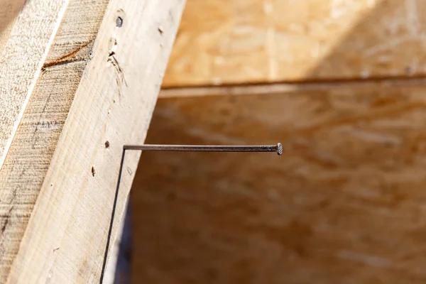 Marangozlar çivi çakmak için çekiç, ustalar ve inşaat malzemeleri kullanır. Bir adam, tahta bir kirişe demir bir çivi çakıyor.