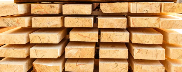 Stack of new wooden studs at the lumber yard. Timber on the construction site to dry. Background of sawed and processed wood of coniferous breeds. — Stock Photo, Image