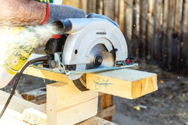 Ahşap meta-meta üzerinde elle yapılmış dairesel testere. İnşaat alanında bir adam ahşap bir levhayı yakından kesiyor. Kereste fabrikasında ahşap ile çalışma kavramı. Ahşap işçiliği.