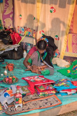Kimliği belirlenemeyen orta yaşlı bir Hintli kadın, Kolkata 'da el sanatları fuarında satılık renkli el işi eşyalar boyuyor. Batı Bengal, Hindistan 'da kırsal endüstri, Aralık 2019