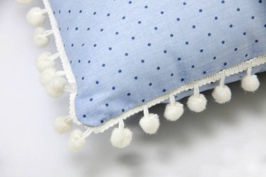 Yastık. Kenarları ponpon olan mavi yastığın detayları. Beyaz arkaplan, yakın plan