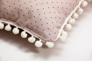 Yastık. Kenarları ponpon olan yastık detayları. Beyaz arkaplan, yakın plan