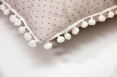 Yastık. Kenarları ponpon olan yastık detayları. Beyaz arkaplan, yakın plan
