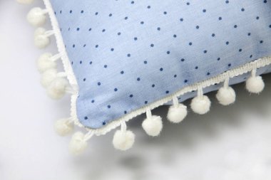 Pomponları ve beyaz arkaplanda benek desenleri olan samimi mavi yastığın ayrıntıları