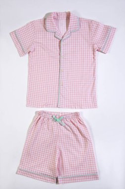 Güzel pembe bebek kıyafetleri, beyaz arka planda damalı pijamalar.