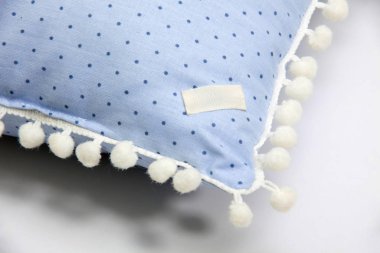 Pomponları ve beyaz arkaplanda benek desenleri olan samimi mavi yastığın ayrıntıları