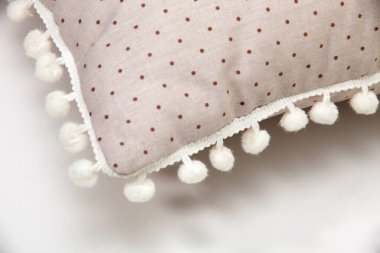 Beyaz zemin üzerinde ponpon ve puantiyeli rahat bej yastık desenleri