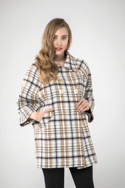 Güzel moda kadını stüdyoda şık kıyafetler içinde poz veriyor.