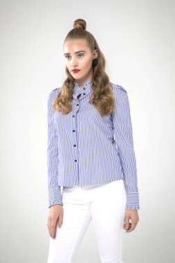 Güzel moda kadını stüdyoda şık kıyafetler içinde poz veriyor.