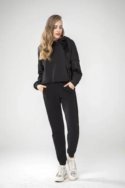 Güzel moda kadını stüdyoda şık kıyafetler içinde poz veriyor.