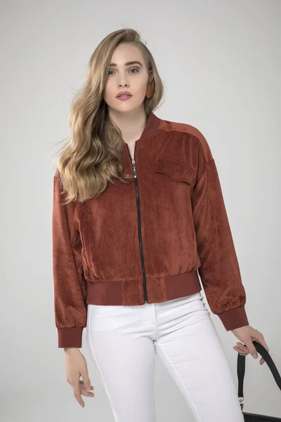 Güzel moda kadını stüdyoda şık kıyafetler içinde poz veriyor.
