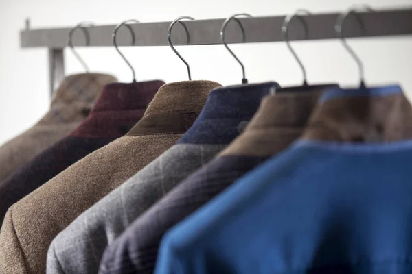 close up of male suits hanging on white background