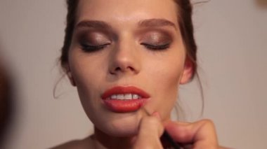 Genç bir kadın için makyaj sanatçısı dudakları boyuyor