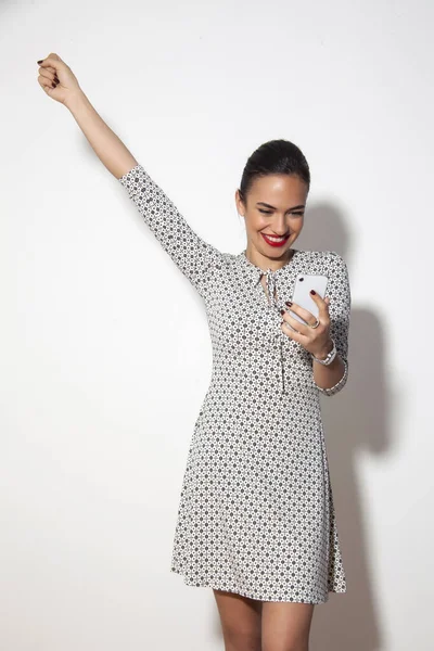 Woman Raising Her Hand While Checking Her Phone Smiling — Stock Photo, Image