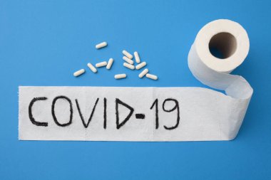 Coronavirus salgını covid 19 mavi arka planda bir rulo tuvalet kağıdına beyaz haplarla yazılmış..