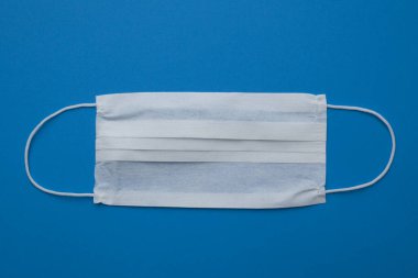 Yüz harcanabilir tıbbi maske mavi arkaplanda izole edildi.