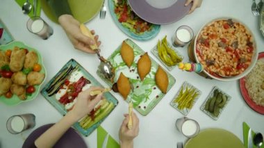 Geleneksel lezzetli bir Türk aile sofrası manzarası. Turşu, tavuk pilavı, domatesli kayısı fasulyesi, kibbe, hamur işi, kızarmış sebze ve yeşil fasulye. Aile kendilerine hizmet ediyor..