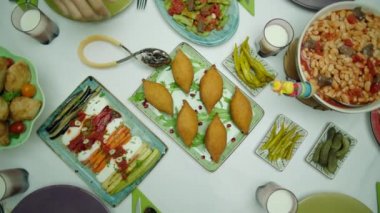 Geleneksel lezzetli bir Türk aile sofrası manzarası. Turşu, tavuk pilavı, domatesli kayısı fasulyesi, kibbe, hamur işi, kızarmış sebze ve yeşil fasulye. Aile kendilerine hizmet ediyor..