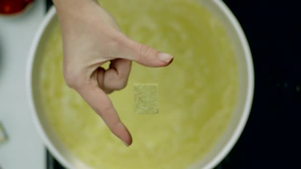 Woman's hand throwing seasoning dice into soup — Stock Footage Woman Hand Throwing Seasoning Dice Soup Stock Footage