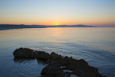 Sahilde güzel bir gün batımı. Kayalar ve deniz.