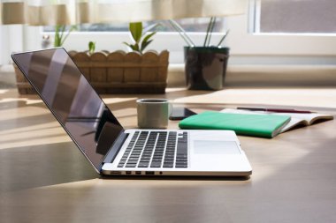 Bilgisayar, kalem, defter, cep telefonu ve kahve masanın üstünde. Ders, çalışma masası. Online eğitim. Merkez ofis. yan görünüm.