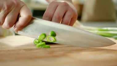 Kesme tahtasında yeşil biber doğrayan eller sonra da bıçakla biber fırlatıyor. Çabuk!