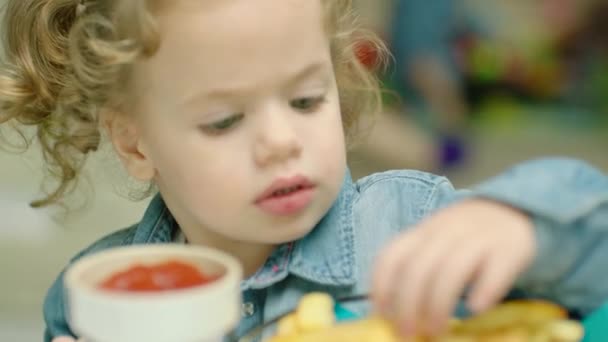 귀여운 소녀가 손가락으로 감자튀김을 그것들을 케첩에 담근다 — 비디오