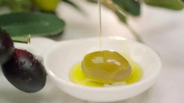 Çiğ yeşil zeytinlere damlayan zeytin yağı. Zeytin ağacı dalından zeytin yağı dökülüyor. Yakın çekim yeşil zeytin.