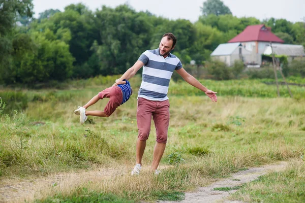 Père jouant et tournant avec son fils dans le parc — Photo