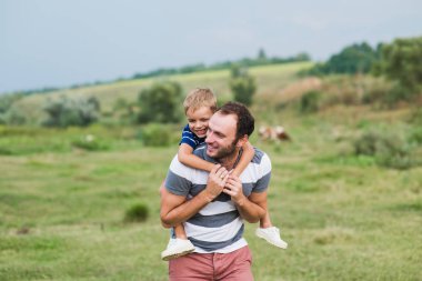 Babasının omuzlarında oturan çocuk.
