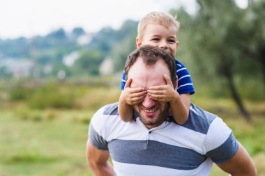 Mutlu çocuk babasının sırtına sürme ile zevk
