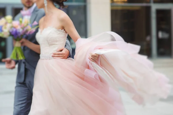 Noiva de luxo segurando um vestido voador e andando — Fotografia de Stock