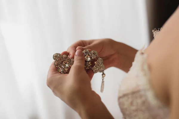 Bride is holding earrings — Stock Photo, Image