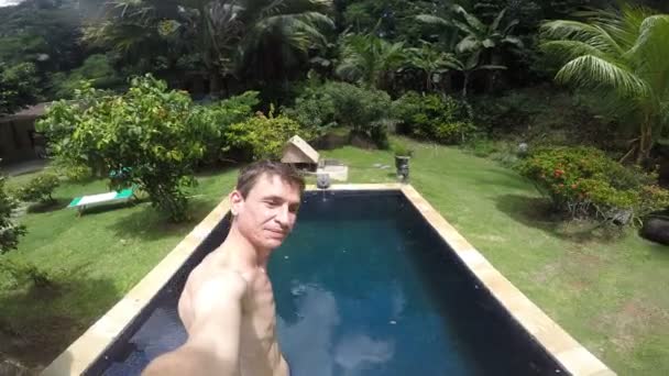 Un hombre salta a la piscina, disparándose a sí mismo — Vídeo de stock