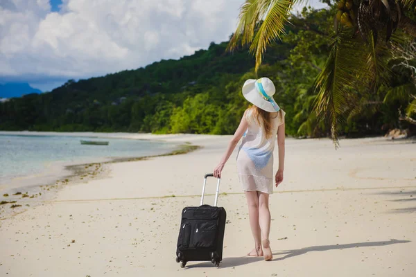 Kobieta z walizką na tropikalnej plaży. — Zdjęcie stockowe