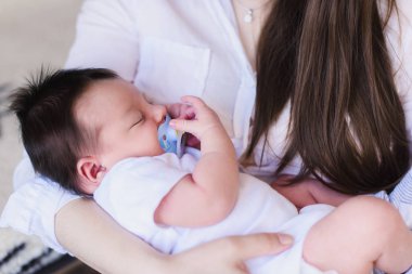 Yeni doğmuş çocuğunu tutan genç anne