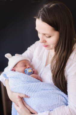 Yeni doğmuş çocuğunu tutan genç anne.