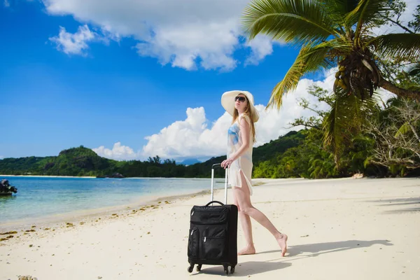 Reiziger meisje met bagage op een tropisch strand. — Stockfoto