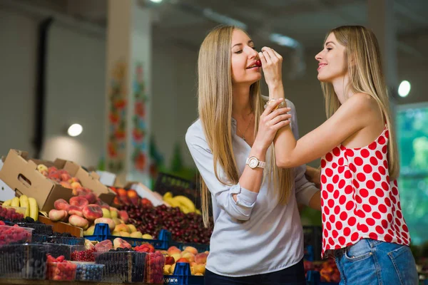 두 여성이 식품 시장에서 체리를 먹으십시오 — 스톡 사진