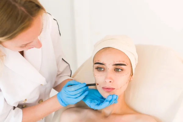 Doctor drawing marks on female face